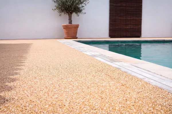 Terraza junto a piscina con stone carpet: pavimento continuo de árido en primer plano